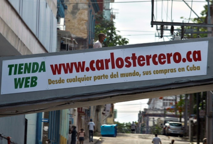 A man walks across a bridge with an advertising of an online store reading âFrom anywhere in the world, your purchases in Cubaâ in Havana on June 17, 2020
