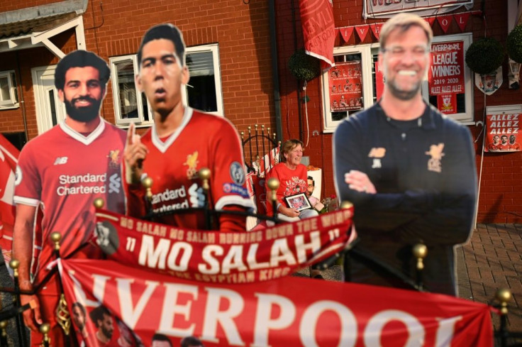 Liverpool fan Emily Farley sits outside her home, decorated with Liverpool banners and cut-outs, as she waits for the result of the match between Chelsea and Manchester City