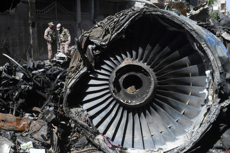 Pakistani security personnel stand beside the wreckage of a PIA aircraft that crashed into a residential area in Karachi in May 2020, killing 97 on board and one on the ground -- the carrier's woes have deepened since the crash
