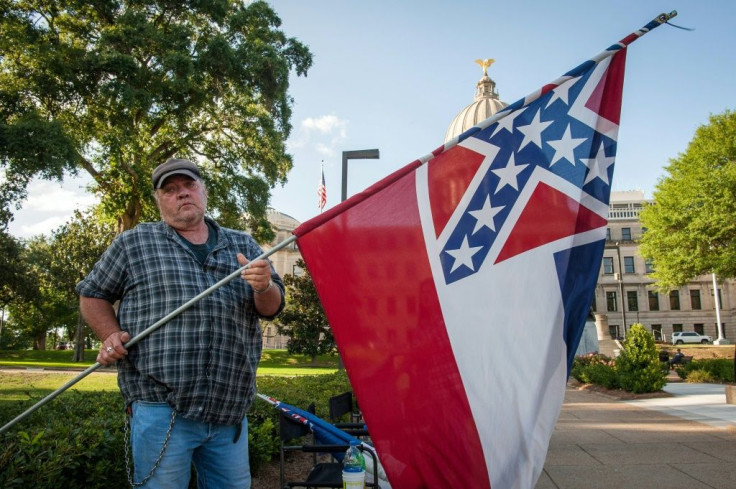 A protestor rolls up the Mississippi flag after the state legislature voted to change it, outside the state capitol building in Jackson, Mississippi on June 28, 2020