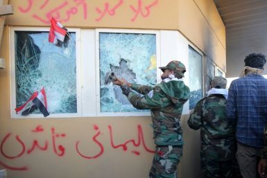 Members of Iraq's Hashed al-Shaabi, a mostly Shiite network of armed groups trained and armed by powerful neighbour Iran, smash a window at the US embassy in Baghdad in December 2019