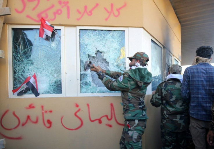 Members of Iraq's Hashed al-Shaabi, a mostly Shiite network of armed groups trained and armed by powerful neighbour Iran, smash a window at the US embassy in Baghdad in December 2019