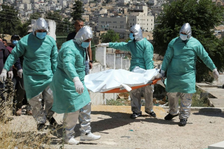 Palestinian health workers transport the body of a coronavirus victim for burial