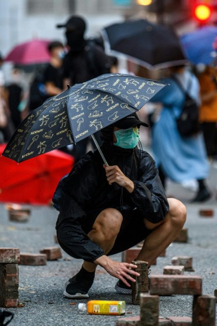 A protester places bricks that were dug up from a nearby sidewalk onto a road during a rally against a new national security law in Hong Kong on July 1, 2020