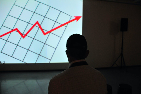 Man wearing white top at projector graph screen