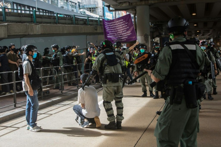 Riot police detain a man and display a flag warning people they may be committing an offence under a new national security law during a protest in Hong Kong