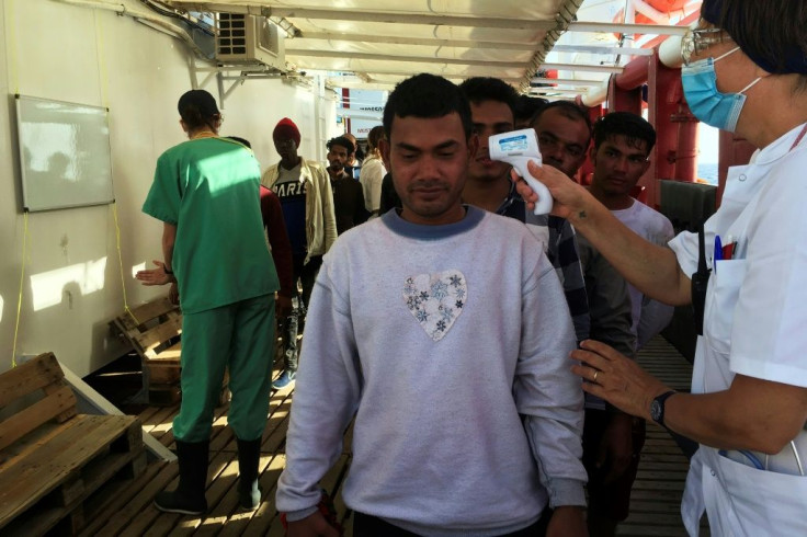 Anne (R) , a medic of French NGO SOS Mediterranee takes the temperature of migrants rescued by members of the boat Ocean Viking, off the coast of Italy's Lampedusa island