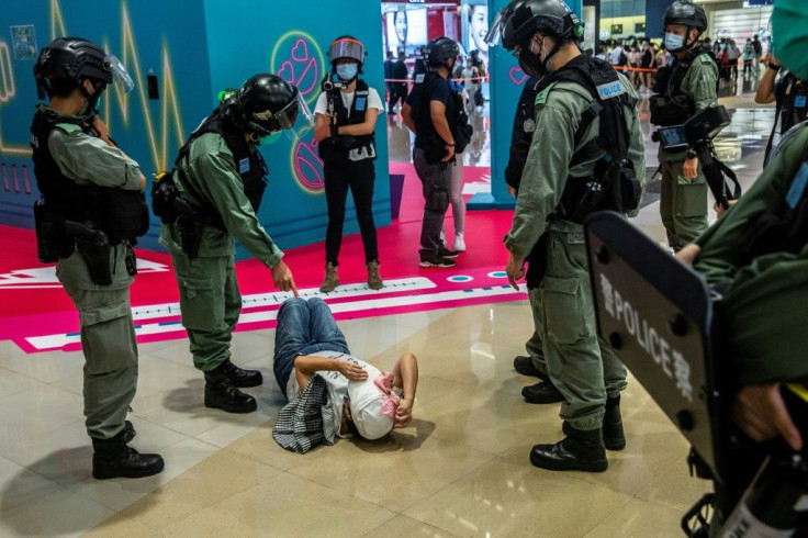 A police officer points at a woman lying on the ground after being searched during a demonstration in a mall in Hong Kong