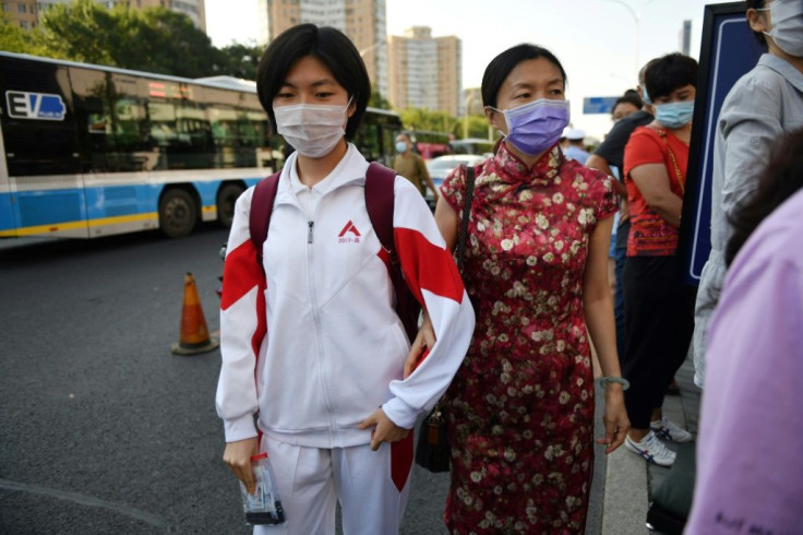 A student arrives with her mother before entering a school to sit the National College Entrance Examination in Beijing