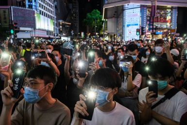 Hong Kong pro-democracy activists hold up their mobile phones during a rally iin June