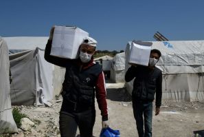 Volunteers deliver aid at a camp for displaced Syrians near the town of Deir al-Ballut, by the border with Turkey, in Syria's Afrin region in the northwest of the rebel-held side of the Aleppo province on April 14, 2020 during the coronavirus pandemic.