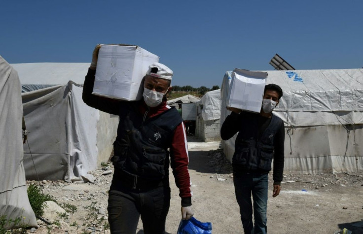 Volunteers deliver aid at a camp for displaced Syrians near the town of Deir al-Ballut, by the border with Turkey, in Syria's Afrin region in the northwest of the rebel-held side of the Aleppo province on April 14, 2020 during the coronavirus pandemic.
