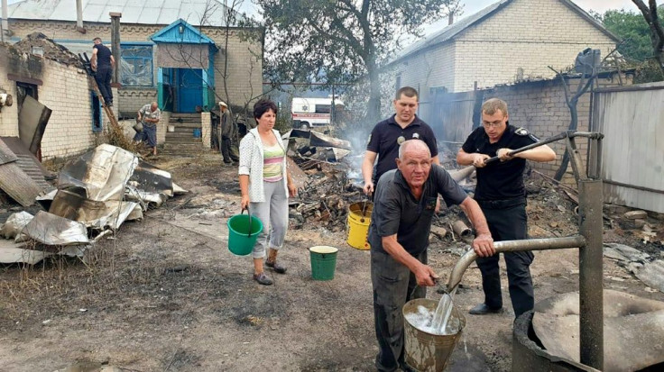 This handout picture from the press service of the Ukrainian State Emergency Service on July 7, 2020 shows residents and police trying to extinguish fires and limit damage in a house, during a wildfire at Novoaydarivsk district, Lugansk region