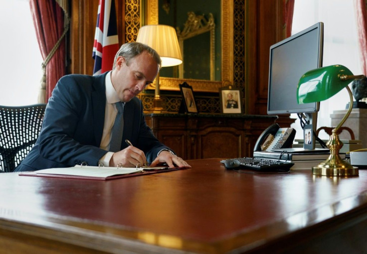 A handout image released by 10 Downing Street, shows Britain's Foreign Secretary Dominic Raab signing a letter to fellow MPs, in the Foreign & Commonwealth Office in central London on July 6, 2020, following the launch of new Human Rights Sanctions