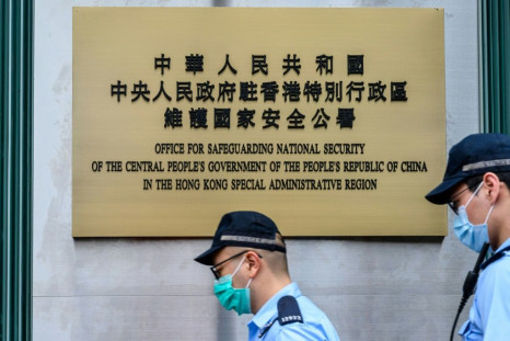 Police walk past a plaque outside the Office for Safeguarding National Security of the Central People's Government in the Hong Kong Special Administrative Region after its official inauguration
