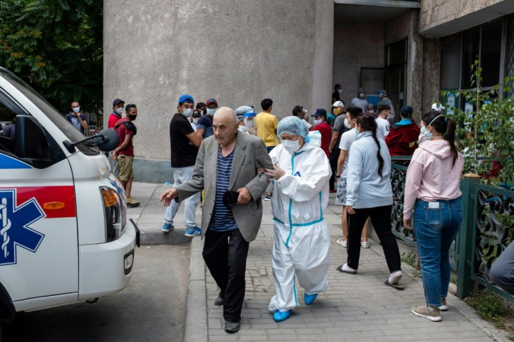 An elderly man is aided outside a medical facility in Bishkek -- many people say a lack of tests of poor quality tests are keeping the official virus case tally low