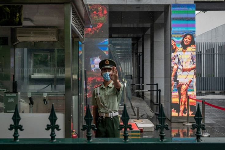 A Chinese paramilitary police officer gestures while standing at the entrance gate of the Australian embassy in Beijing