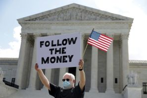 A man holds a sign outside the Supreme Court as it issued rulings in two cases involving the release of President Donald Trump's financial records