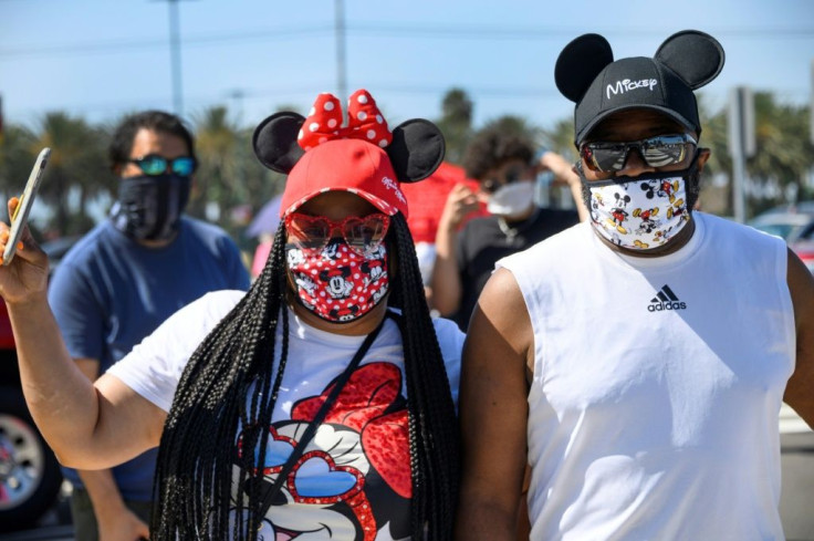 A couple waits in line to enter Downtown Disney in Anaheim, California the first day the outdoor shopping and dining complex has been open to the public since it closed in mid-March due to COVID-19