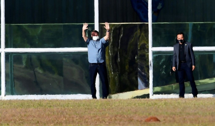 Brazilian President Jair Bolsonaro waves outside Alvorada Palace in Brasilia on July 9, 2020