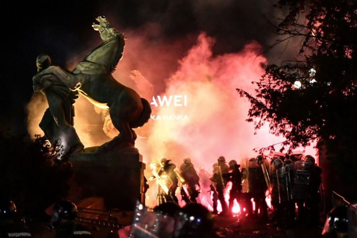 Police stand in tear gas smoke outside the National Assembly building in Belgrade, on July 10, 2020, during clashes with protesters at a demonstration against a weekend curfew announced to combat a resurgence of COVID-19 infections