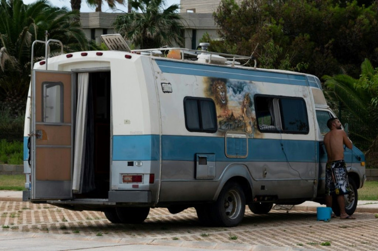 A man shaves in the rearview mirror of his well-travelled motorhome in Castellon