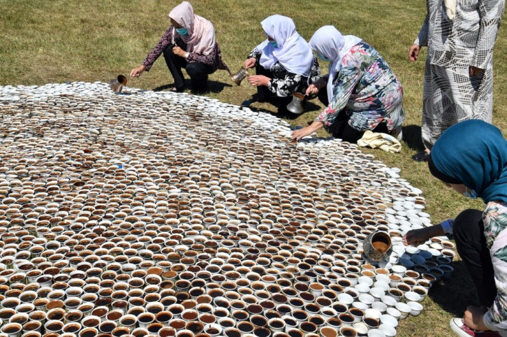Survivors of the massacre help Bosnian artist Aida Sehovic fill up 8,000 coffee cups as part of her installation "Why Aren't You Here"