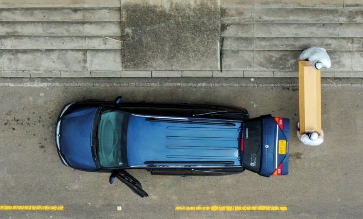 Funeral workers place the coffin of a coronavirus victim in a hearse in Colombia, as Latin America cases surge