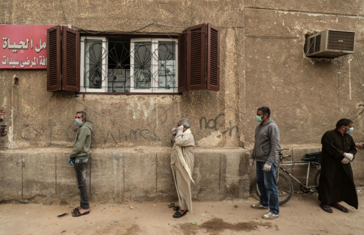 Egyptian men wait outside a centre of non-governmental organisation the Egyptian Food Bank to receive cartons with foodstuffs amid the pandemic on April 5