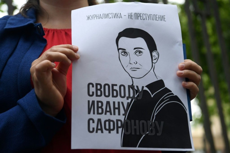 A woman holds a poster featuring an image of Ivan Safronov and the words "Journalism is not a crime"