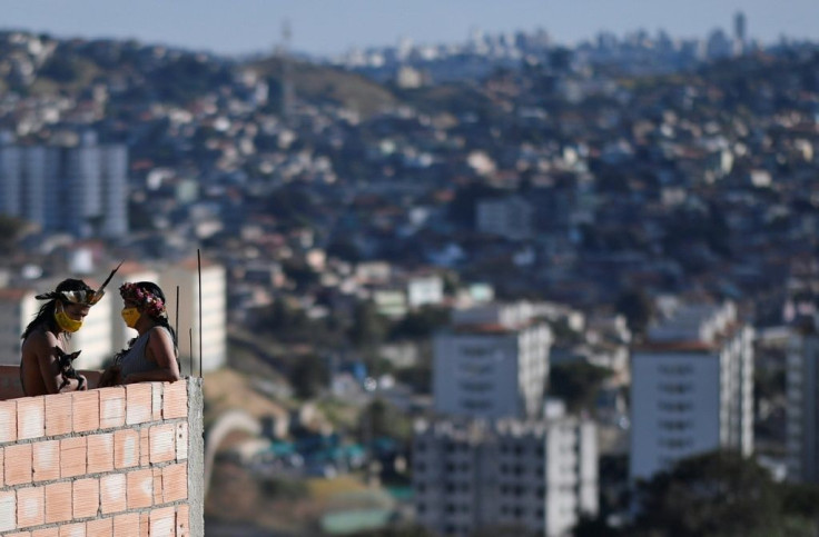 Wearing face masks and head-dresses, members of the Pataxo Ha-ha-hae tribe look out over the concrete jungle of the Vila Vitoria favela near Belo Horizonte, Brazil