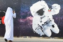 In this file photo from September 2019 a man takes a picture of an illustration of an astronaut with the Emirati national flag outside Dubai's Mohammed Bin Rashid Space Centre