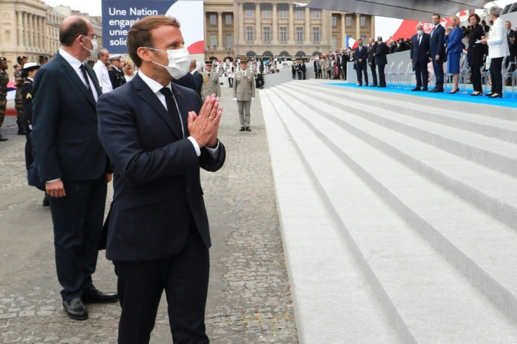 French President Emmanuel Macron wearing a protective facemask greets guests