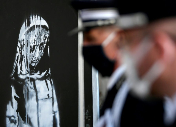 Police officers stand next to the Banksy artwork at the French embassy in Rome