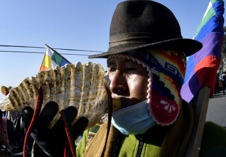 An Amauta, a priest of Bolivia's indigenous Aymara community, blows an instrument during an anti-government march
