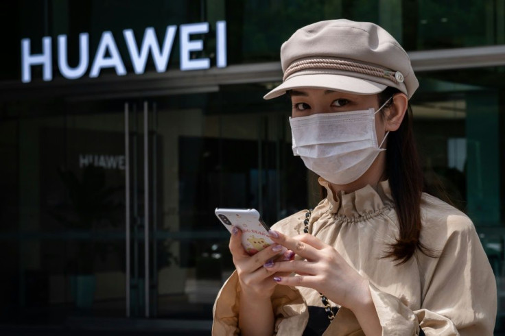 A woman in Beijing walks in May 2020 past a shop of Huawei, the Chinese telecom giant increasingly targeted by the United States