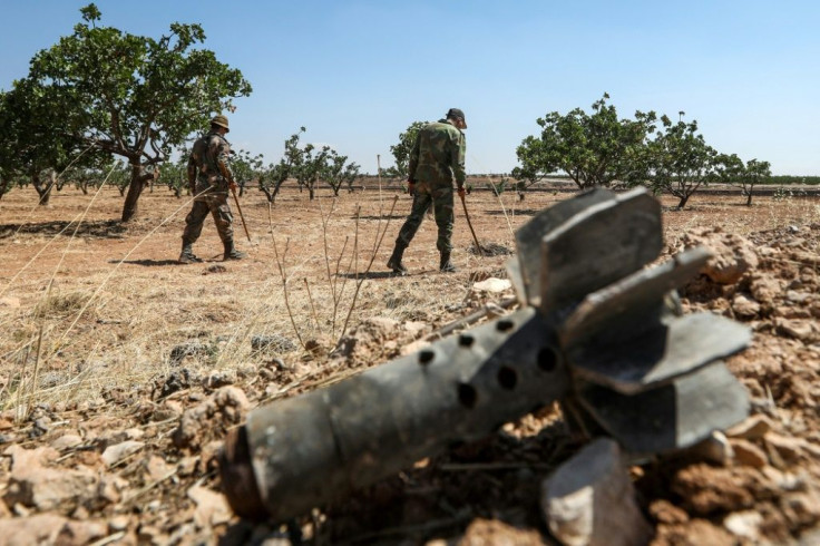 Syrian army soldiers use detectors to find and clear landmines and other unexploded ordnance in a pistachio orchard north of Hama