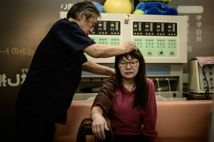 Hiroyuki Mitsuhashi treats a woman who broke her right wrist, using healing techniques of 'judo therapy', designed to speed up the body's natural healing mechanism