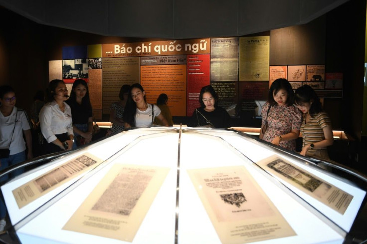 Visitors read historic press articles and newspaper prints displayed at the new museum