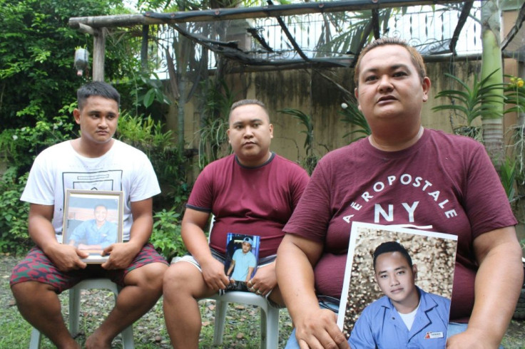 The brothers of Filipino seafarer Cherokee Capajo pose for photos on June 29 while holding his portrait in the central Philippines, where he had to endure a second quarantine