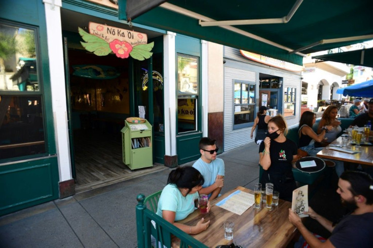 A waitress takes an order at tables temporarily set up in the street on July 16, 2020 outside a restaurant in Huntington Beach, California