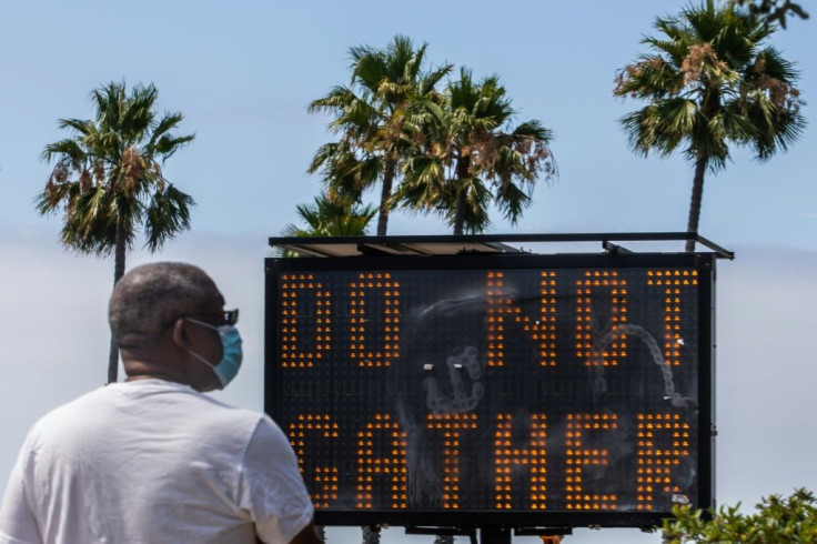In the middle of summer vacation season, a sign urges people not to gather in Long Beach, California