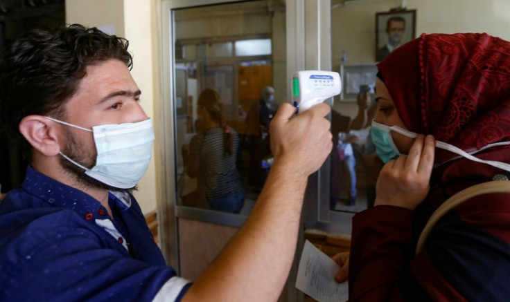 A woman gets her temperature checked before voting at a polling station in the Syrian capital Damascus. Syria has recorded 496 cases of the novel coronavirus including 25 deaths in government-held areas