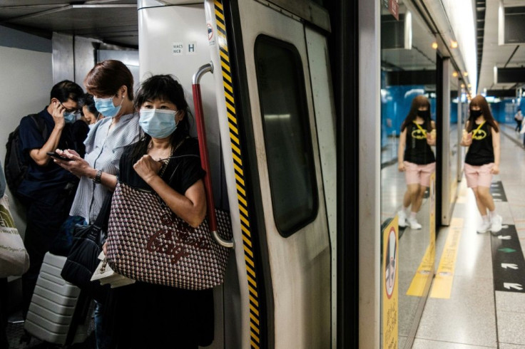 Commuters wear face masks on a metro train in Hong Kong. The city's leader says coronavirus is running "out of control" afater a daily record number of new cases