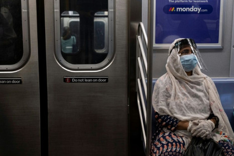 A woman wearing a face mask and shield sits in a New York subway train during rush hour amid the coronavirus pandemic on July 16, 2020; as many people turn away from mass transit, bicycle use has exploded