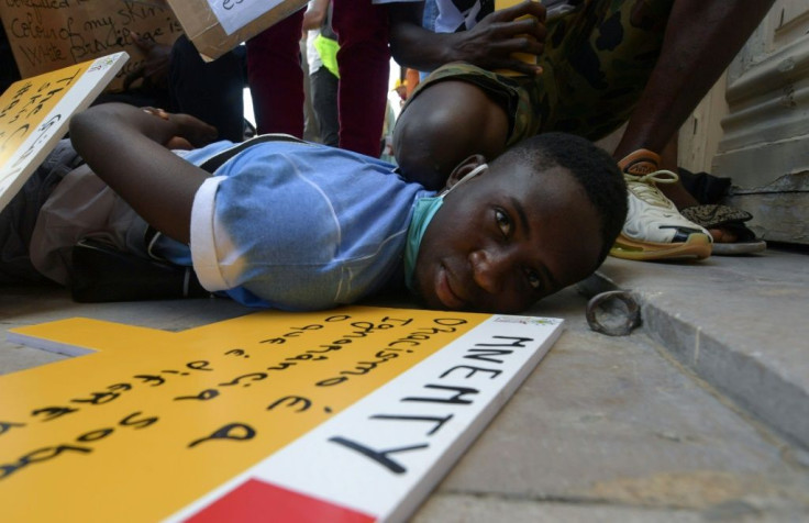 In this file photo from June 6, youths at an anti-racism solidarity rally in Tunisia re-enact the event leading to the death of George Floyd