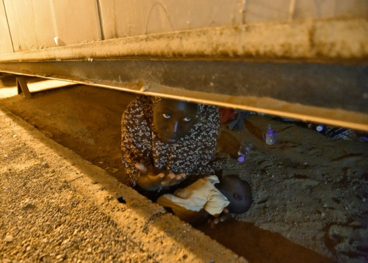 An African migrant from Niger hides with her newborn child as she tries to avoid deportation, in a file image from July 2018 at a transit centre for migrants in southern Algeria