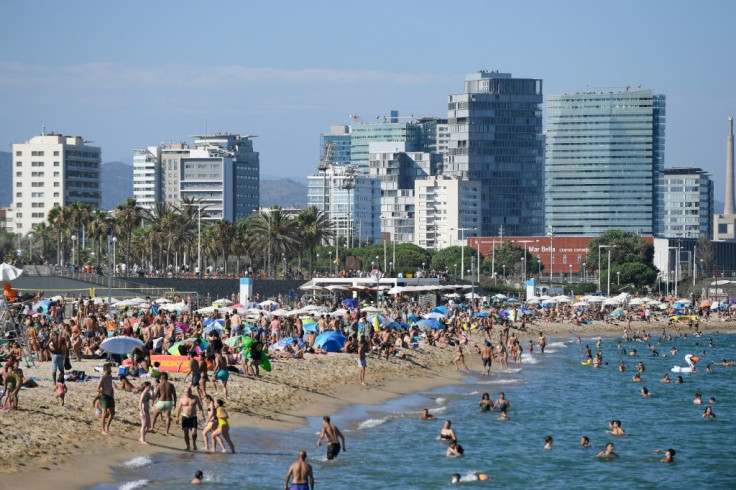 People swim and sunbathe at Bogatell beach in Barcelona, one of the several beaches that had to be closed due to overcapacity