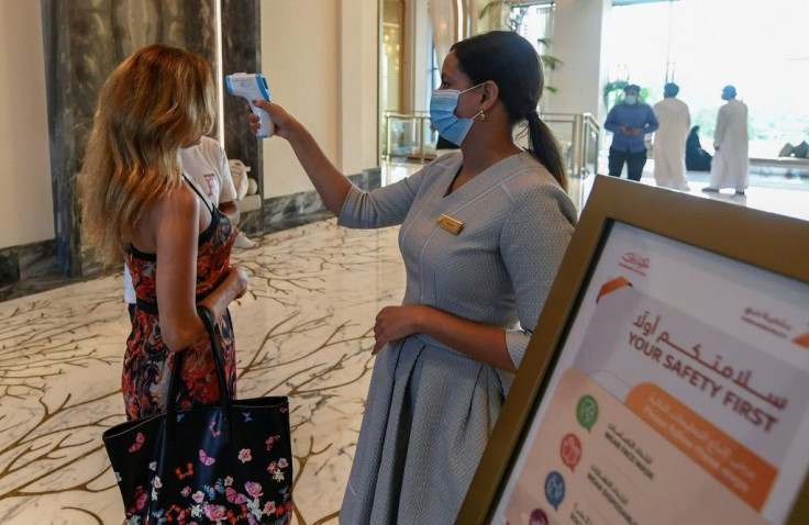 A staff member checks the temperature of a tourist at the Al Naseem hotel in Dubai as the Gulf emirate reopens its doors this month to international visitors after a nearly four-month closure