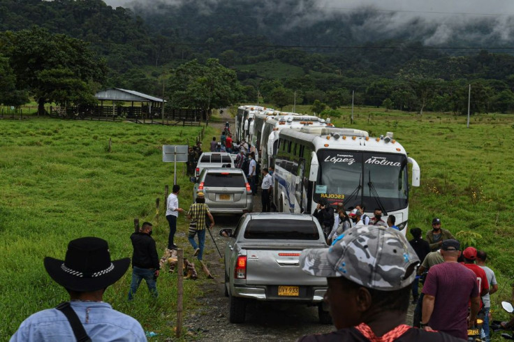 Ex-FARC guerillas walk behind trucks on their way to Mutata, Antioquia department
